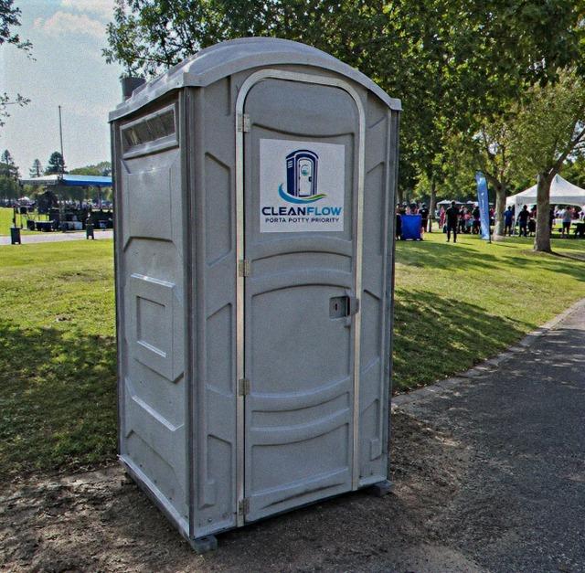 Deluxe flushing portable restroom on grass beside an event pathway