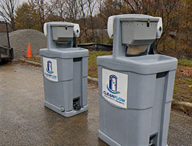 Pair of portable handwash stations with foot pump sinks on a gravel site