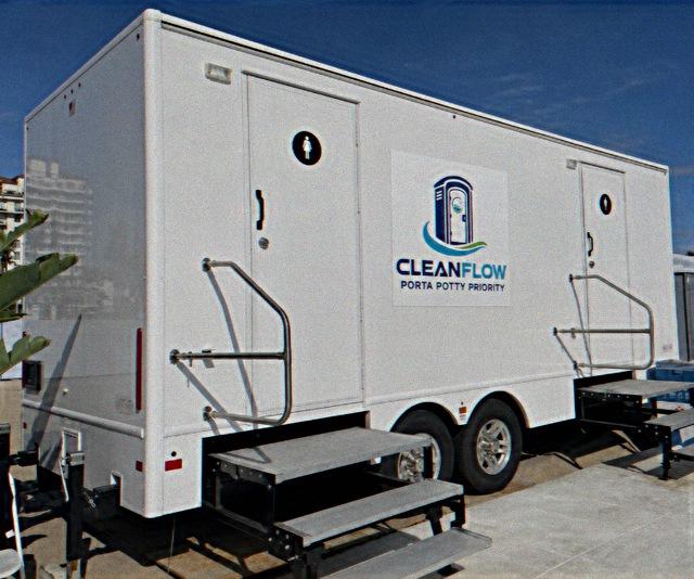 Two station luxury restroom trailer with steps and handrails parked at an event venue
